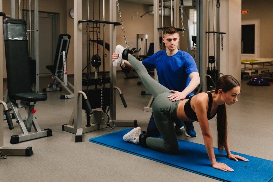 Rehabilitacja: kobieta ćwiczy pod okiem fizjoterapeuty na siłowni.