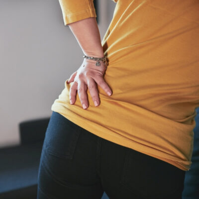 Osoba trzyma się za plecy z powodu bólu spowodowanego przez rwa kulszowa.