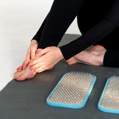 Kobieta masuje stopę na macie, co może pomóc w łagodzeniu objawów zapalenia stawów.