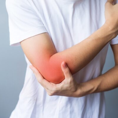 Mężczyzna trzyma się za bolący łokieć, co może sugerować zapalenie stawów.