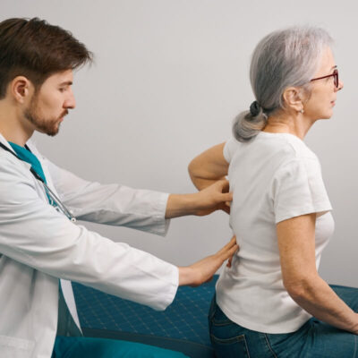 Lekarz badający pacjentkę z bólami kręgosłupa.