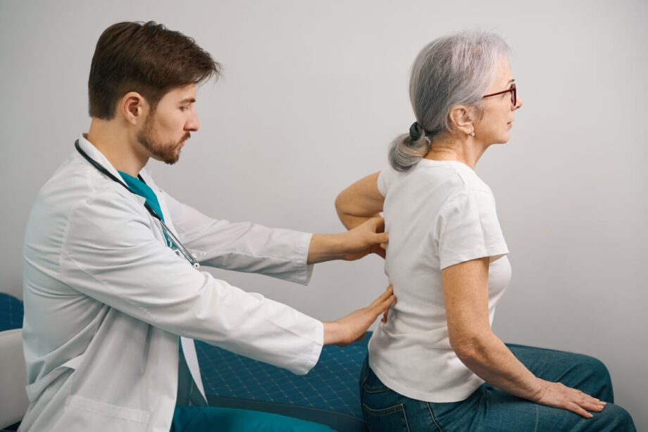 Lekarz badający pacjentkę z bólami kręgosłupa.